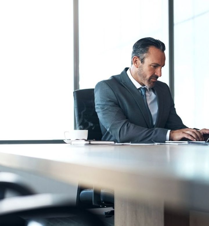 A man sits at a desk working on a laptop computer