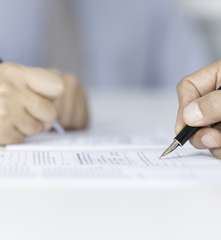 Close up of people's hands as they sign papers.