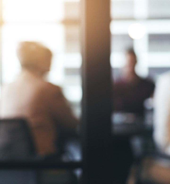 Blurred image of people sitting at a boardroom table.