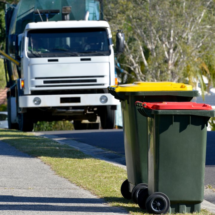 Rubbish bins with rubbish truck in background lifting a bin 2