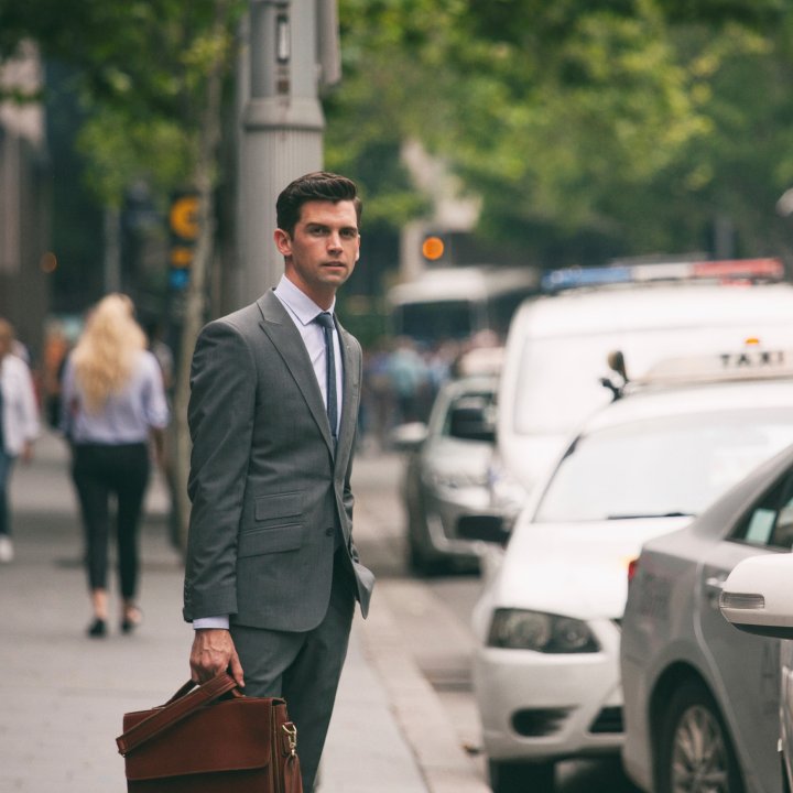 main with briefcase in suit standing next to taxi